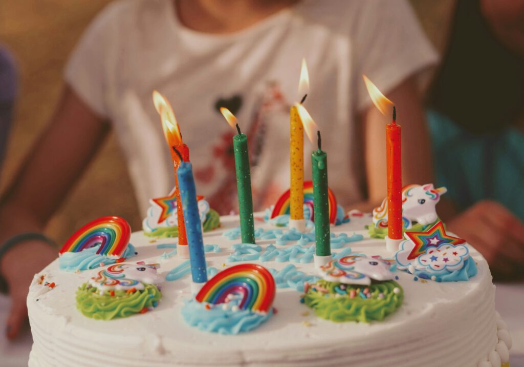 Colorful birthday cake with candles in front of child.
